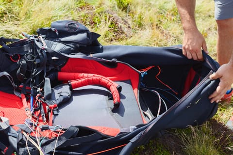 A paraglider checks the harness before strapping in