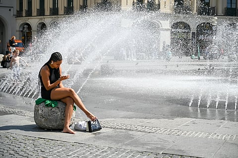 A woman cools down near a fountain in Munich, Germany