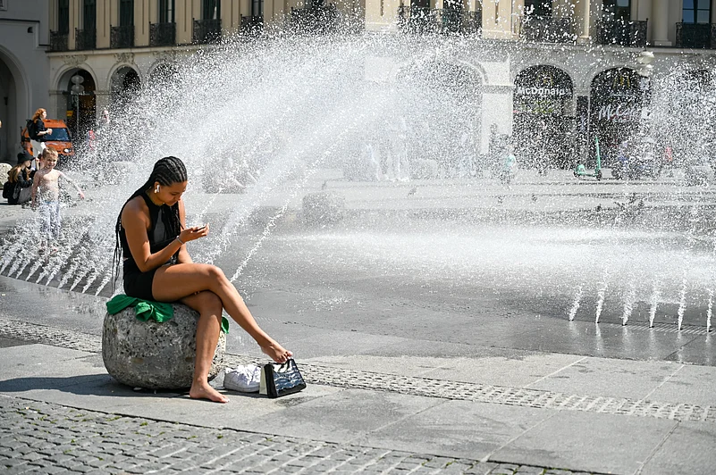 A woman cools down near a fountain in Munich, Germany