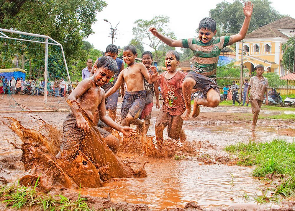 Children run and play in the mud during the Chikhal Kalo festival