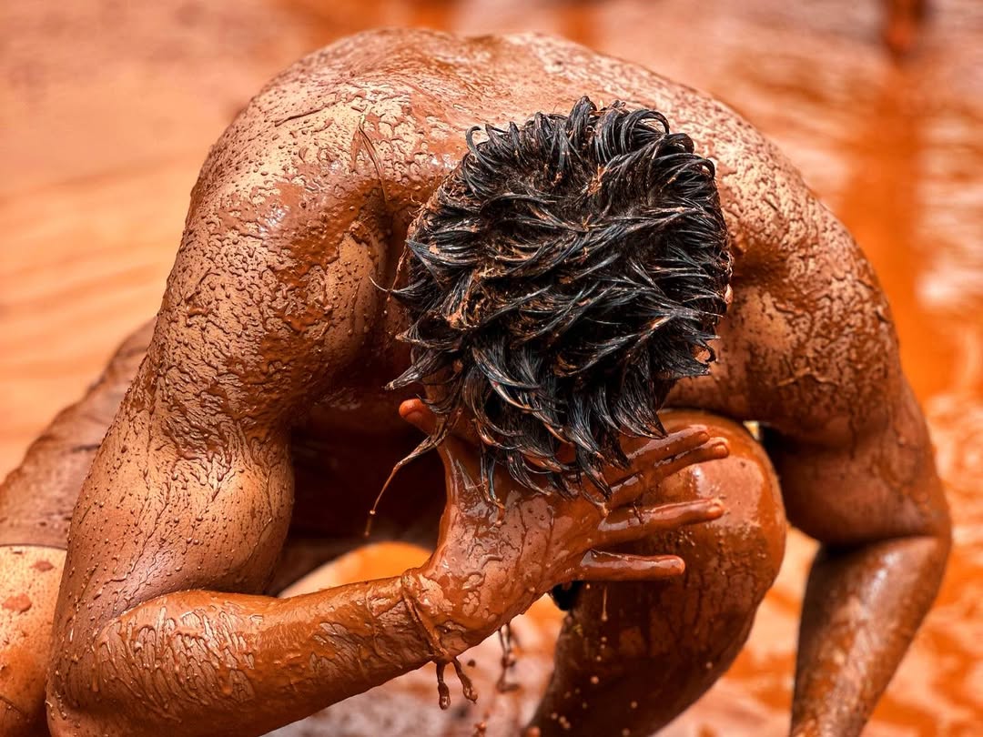 Participants apply oil to their bodies before entering a mud-filled courtyard during the Chikhal Kalo