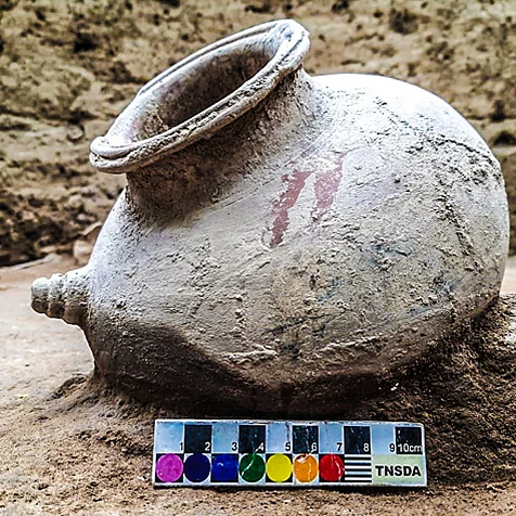 A beautifully preserved red-slipped pot with a lateral spout and decorative grooves, likely used for pouring liquids during rituals or daily life. Its form and finish reflect advanced ceramic craftsmanship