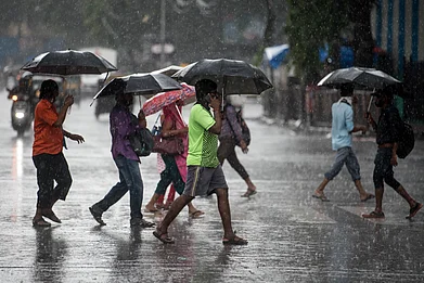 Manoej Paateel/Shutterstock : People cross a road in Mumbai as heavy rainfall lashes the city in 2020