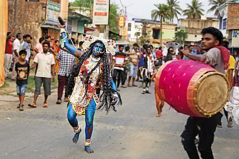 A Hajra Puja participant dressed as a deity attending Lord Shiva’s wedding to Nilavati, charges through the street dramatically, brandishing a weapon