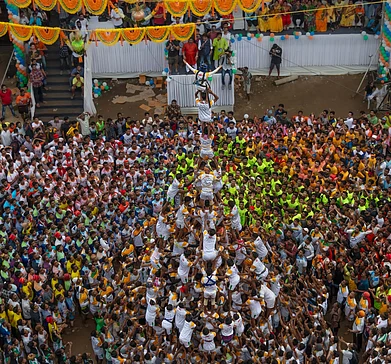 Sandycinecam/Shutterstock : The dahi handi involves participants forming human pyramids to reach and break a clay pot suspended high above the ground