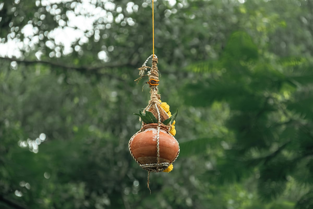 In a dahi handi, a clay pot filled with curd, butter and other items like fruits and coins is tied high above the ground