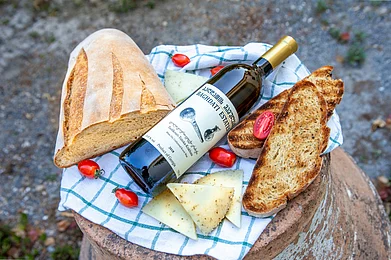 Photo by ALEXANDRA TORRO on Unsplash : A bottle of Georgian natural wine with fresh bread, cheese, and cherry tomatoes