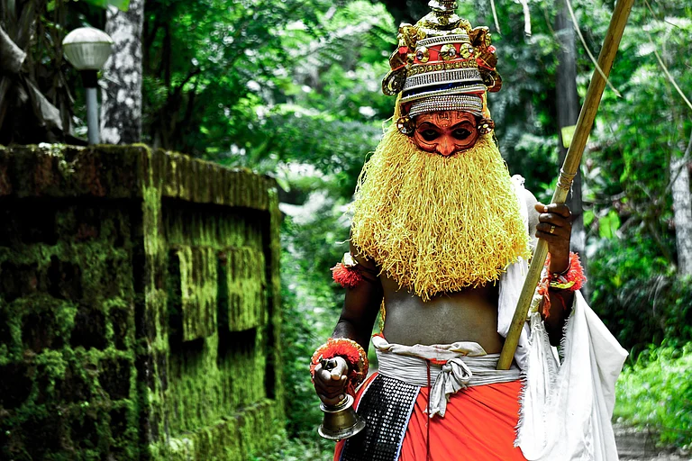 Red robes, palm-leaf umbrella, and silence—Onapottan blessing households in North Kerala - Shutterstock