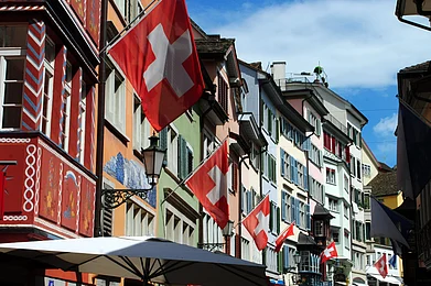 BlueJacaranda/Shutterstock : Colourful houses and Swiss flags line a street in Zürich