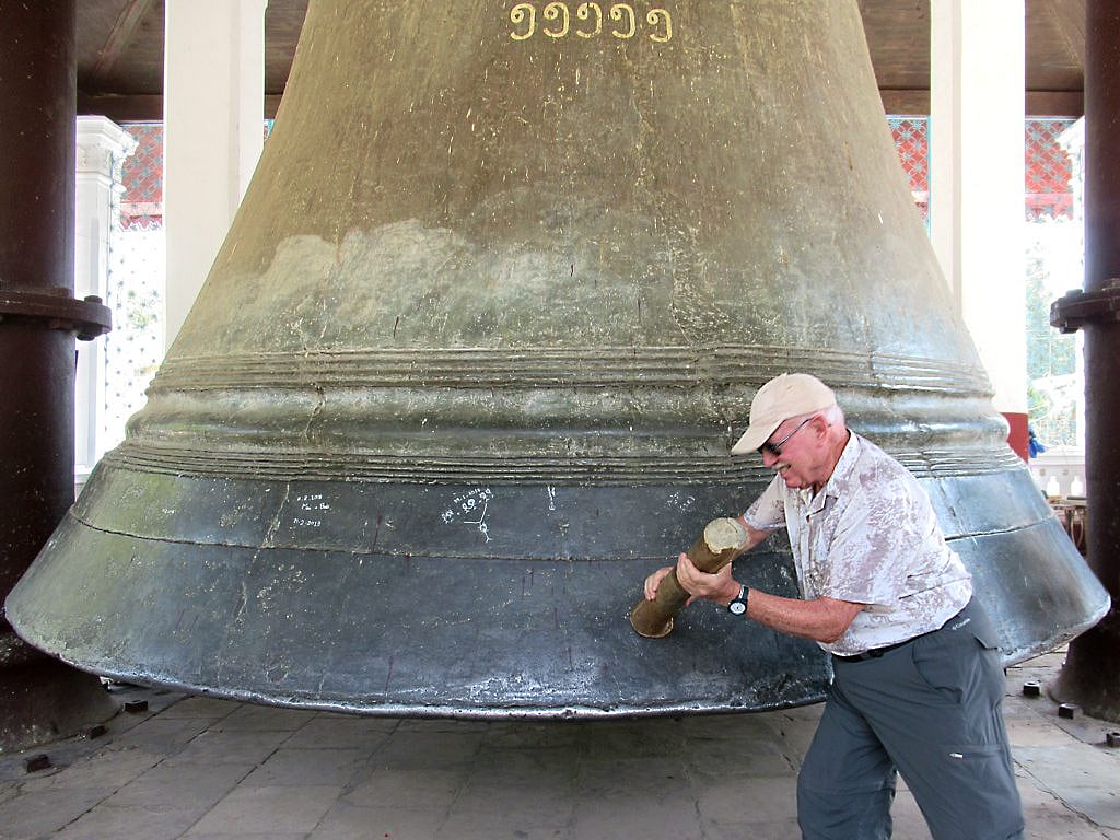 Visitors strike the bell with a large wooden mallet
