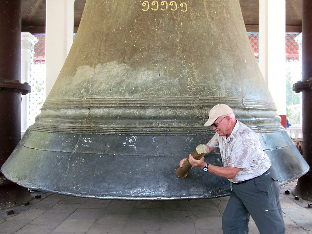 Visitors strike the bell with a large wooden mallet