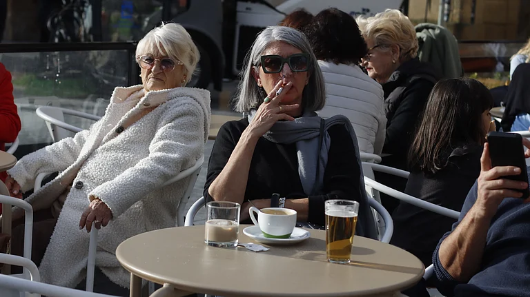 A woman smoking at an outdoor seating in Spain - Shutterstock