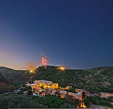 An aerial view of Samode Palace
illuminated under the night sky, as fireworks paint the Aravallis in celebration