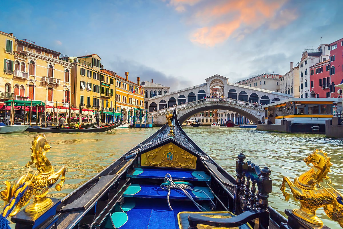 Panoramic view of Canal Grande with gondola and Rialto Bridge at sunset, Venice