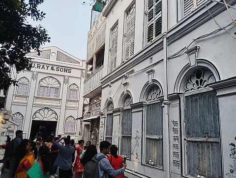 A Durga Puja pandal featuring a striking monochrome theme, adorned with black-and-white sketches and artworks on its walls, blending seamlessly with the surrounding festive neighbourhood atmosphere