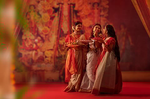 Girls in red-and-white sarees bring the spirit of Pujo alive, celebrating tradition, devotion, and community joy.
