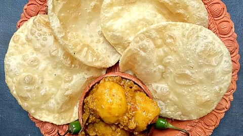 A steaming plate of luchi and aloor dom—a quintessential Bengali treat savoured during Durga Puja.