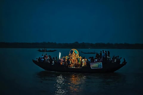 Idols are carried by boat to the midpoint of the river at the international border