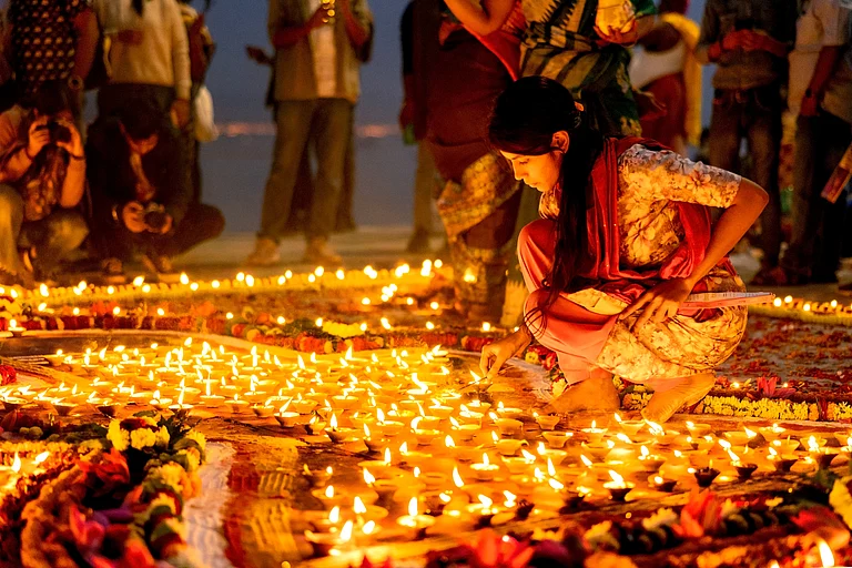 Devotees light earthen lamps along the Ganga, illuminating the ghats - Shutterstock