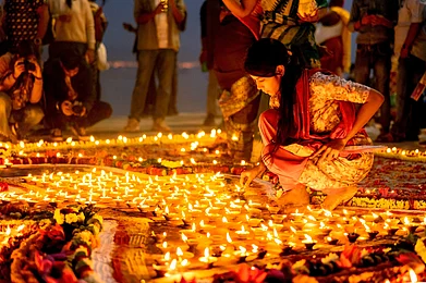 Shutterstock : Devotees light earthen lamps along the Ganga, illuminating the ghats
