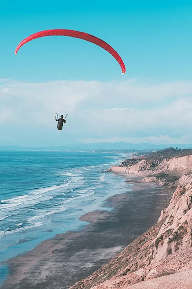 Unsplash : A paraglider hovers above a beach