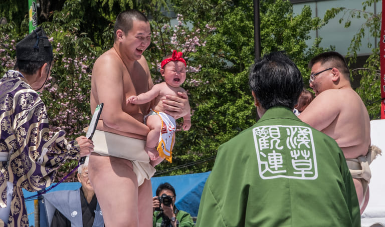 Sumo wrestlers hold infants during the Naki Sumo Festival at Sensoji Temple, Tokyo - Shutterstock