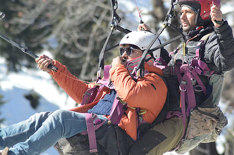 Adventure seekers enjoy paragliding amid the summer beauty