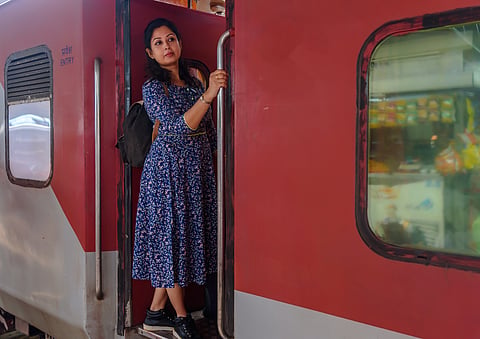 A solo traveller looks out from a moving train