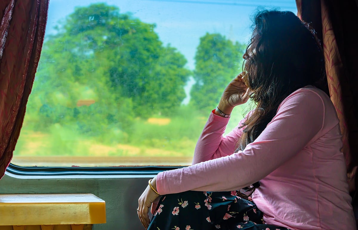 A passenger gazes out of a train window, lost in thought