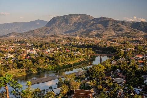 Golden hour view of Luang Prabang with the Nam Khan River and mountain backdrop