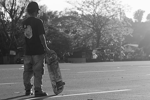 A young skater pauses along Marcos Highway, captured in timeless black and white