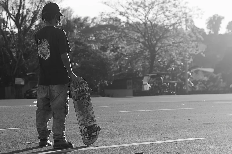 A young skater pauses along Marcos Highway, captured in timeless black and white