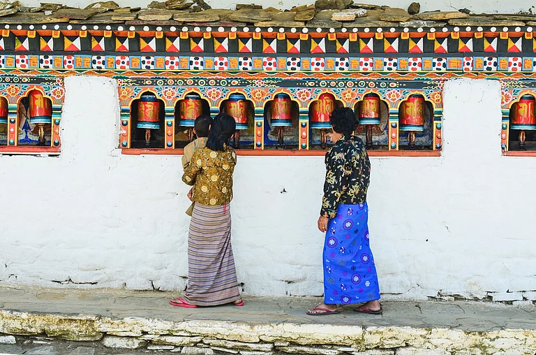 Bhutanese pilgrims spin prayer wheels at Chimi Lhakhang in Punakha - Shutterstock