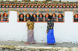 Shutterstock : Bhutanese pilgrims spin prayer wheels at Chimi Lhakhang in Punakha