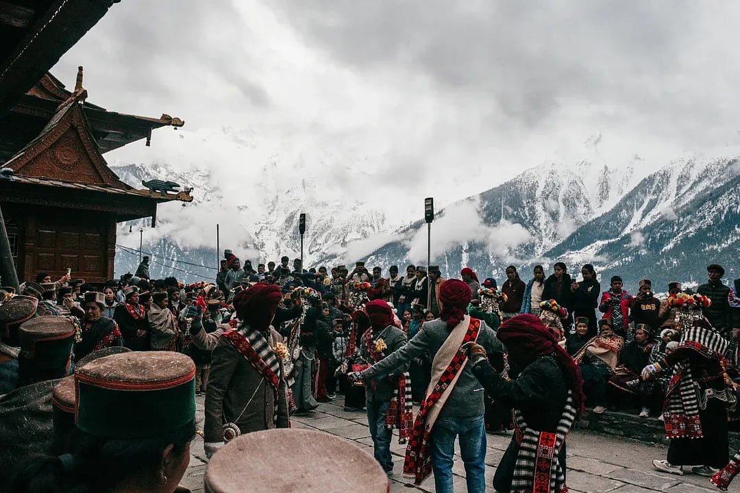 People watch the procession of the Raula and Raulane performers during the Raulane festival in Kinnaur, featuring slow ritual movement and traditional music.