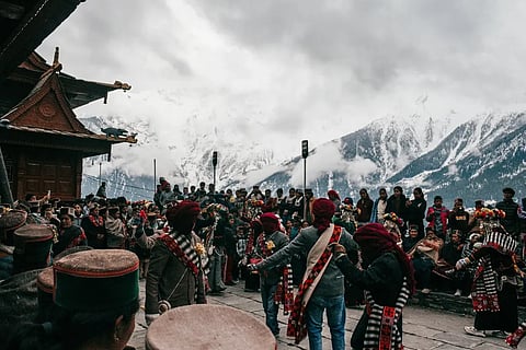People watch the procession of the Raula and Raulane performers during the Raulane festival in Kinnaur, featuring slow ritual movement and traditional music.