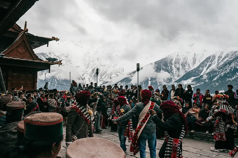 People watch the procession of the Raula and Raulane performers during the Raulane festival in Kinnaur, featuring slow ritual movement and traditional music.