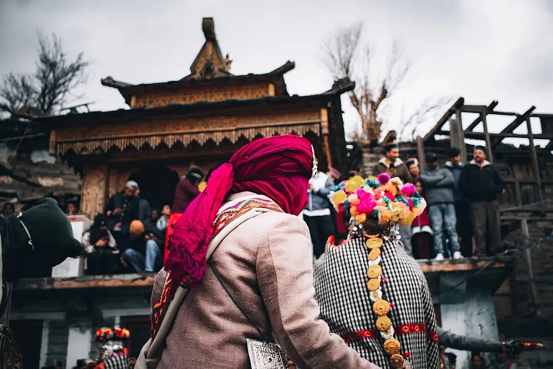 Two villagers wearing traditional wooden masks and Kinnauri attire during the Raulane festival, a centuries-old ritual in Himachal Pradesh