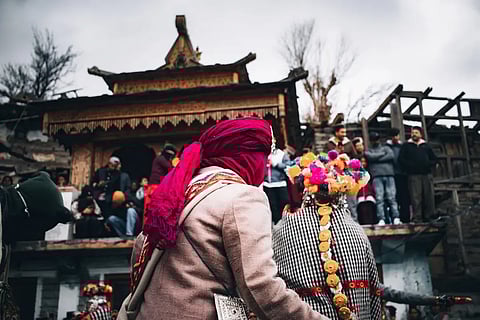 Two villagers wearing traditional wooden masks and Kinnauri attire during the Raulane festival, a centuries-old ritual in Himachal Pradesh
