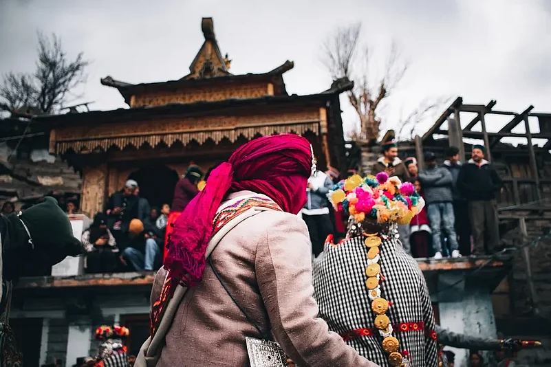 Two villagers wearing traditional wooden masks and Kinnauri attire during the Raulane festival, a centuries-old ritual in Himachal Pradesh