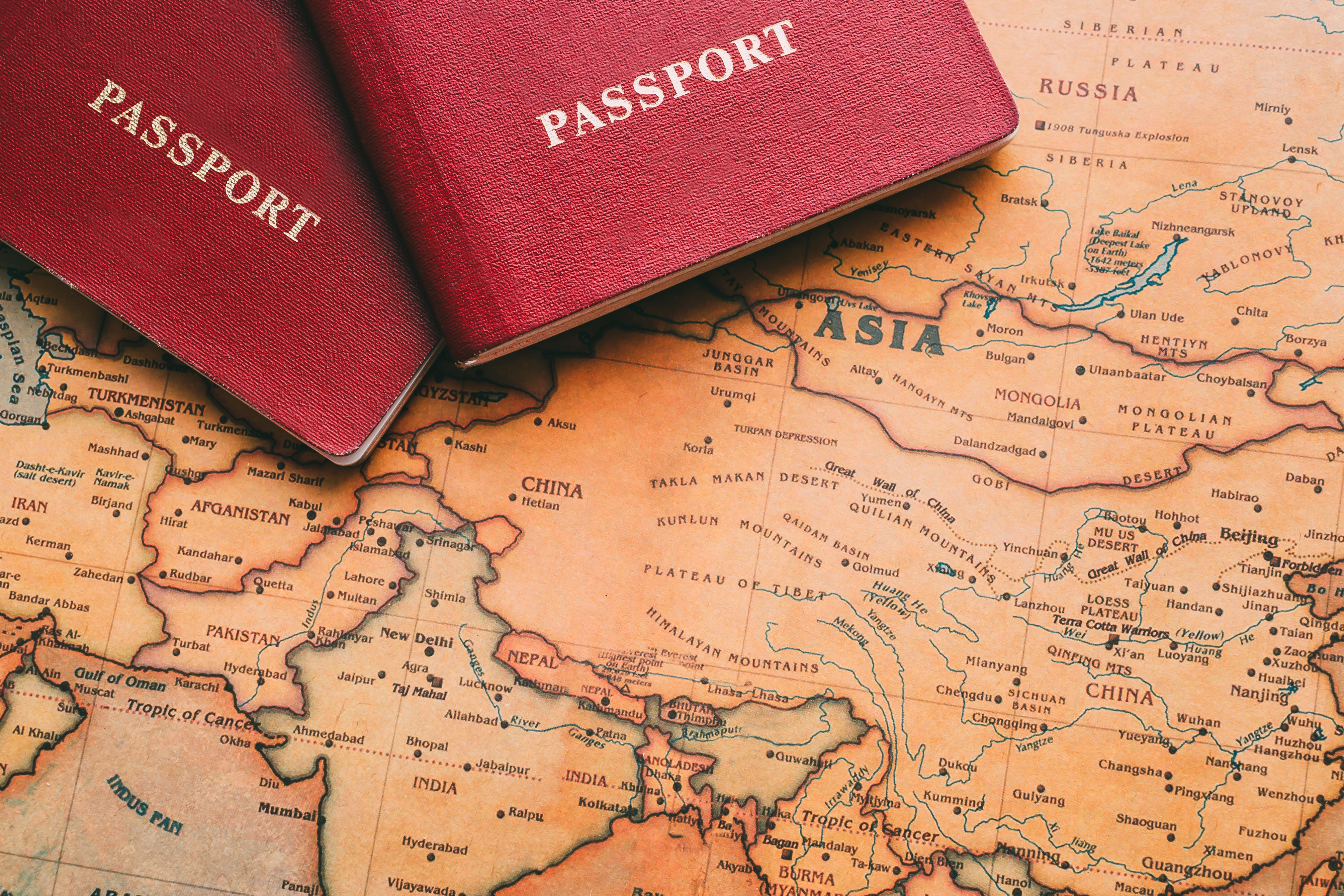 Two passports placed on a world map, symbolising travel across Asia