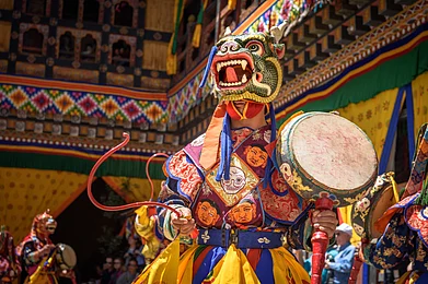 Shutterstock : Monk playing the drums and dancing during the vibrant mask performances of Paro Tsechu