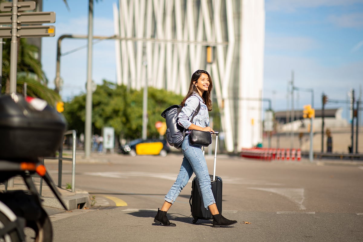 A traveller walking down the street with her luggage