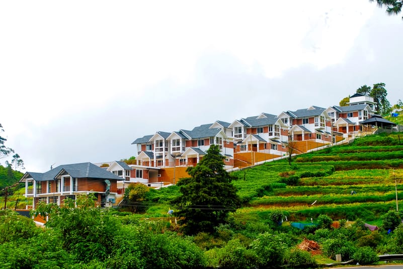 Lush mountains and drifting clouds frame the serene village landscape of Ooty in the Nilgiris