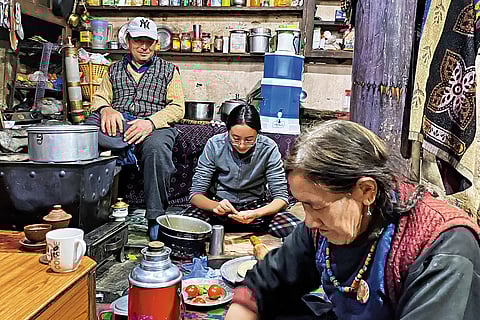 The homestay host, Sonam (centre), prepares dinner with her grandparents in the family kitchen