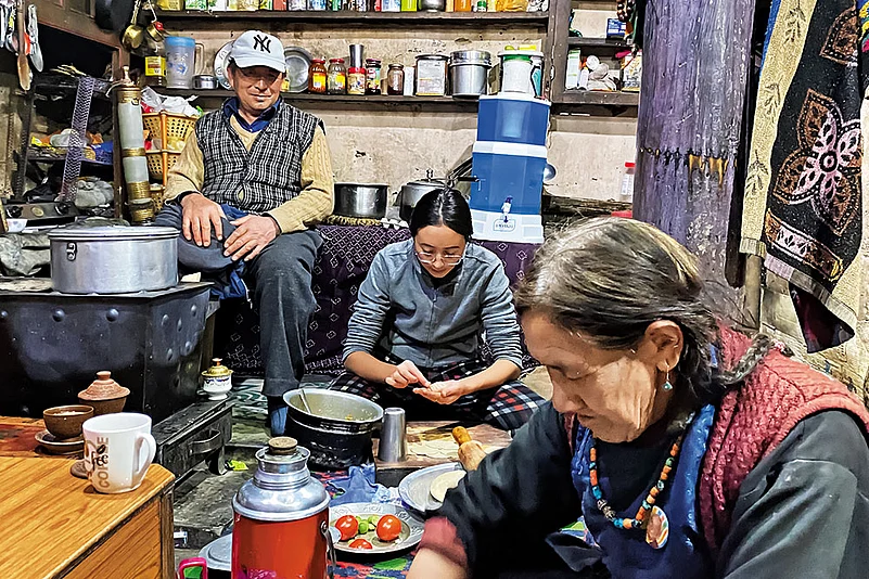 The homestay host, Sonam (centre), prepares dinner with her grandparents in the family kitchen