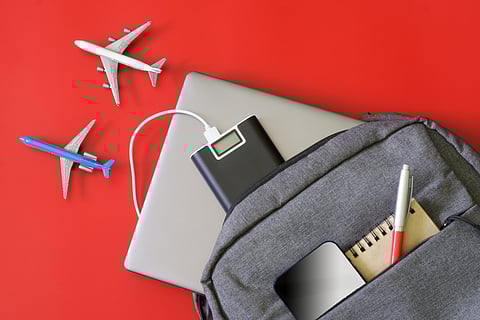 A backpack and travel gadgets set beside toy aircrafts