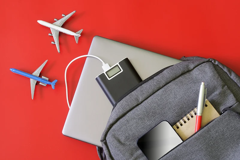 A backpack and travel gadgets set beside toy aircrafts