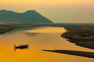 Jimmy Kamballur/Shutterstock : Silhouette of a man rowing a boat on Brahmaputra river, Assam