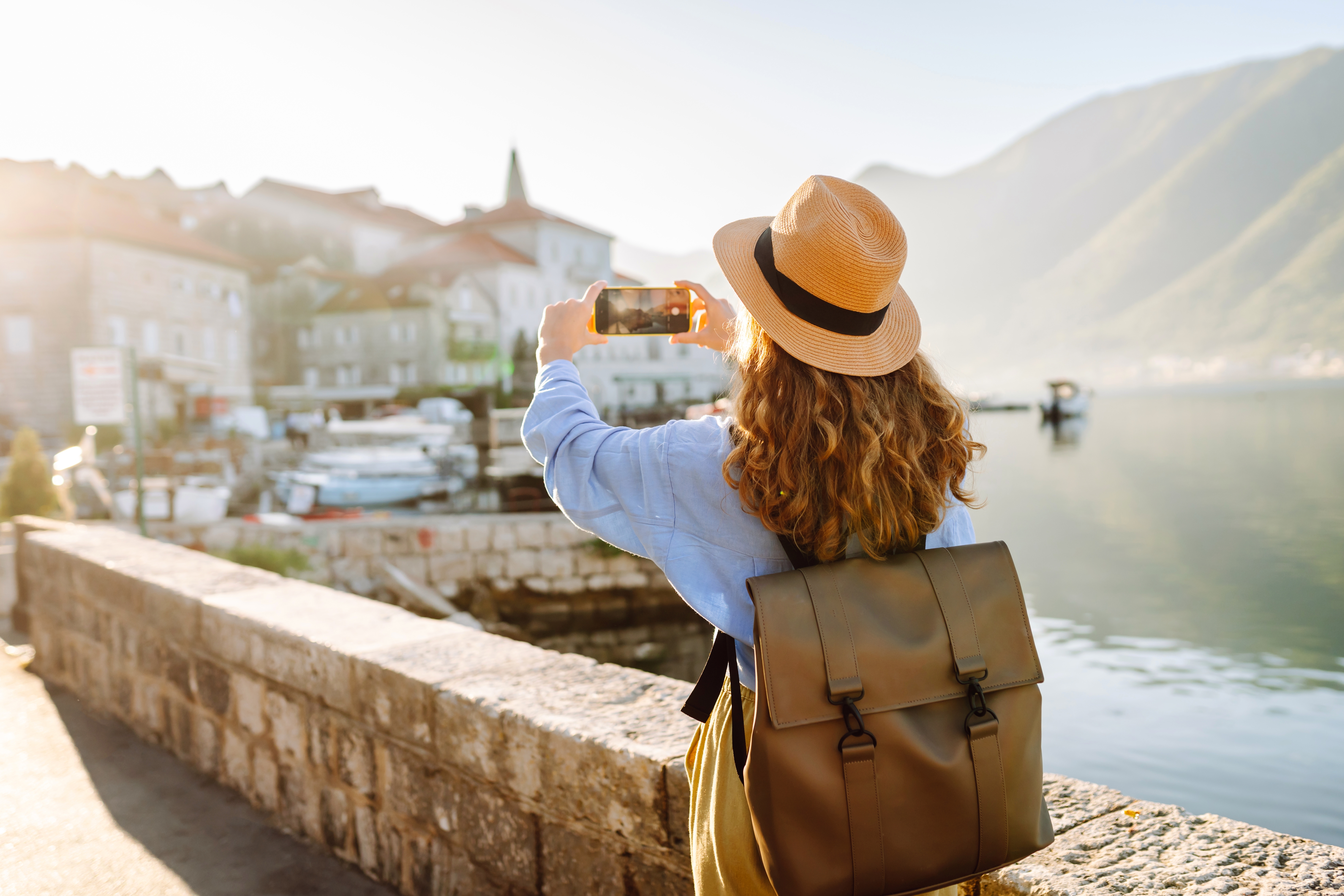 A woman captures a scenic landscape on her smartphone while travelling